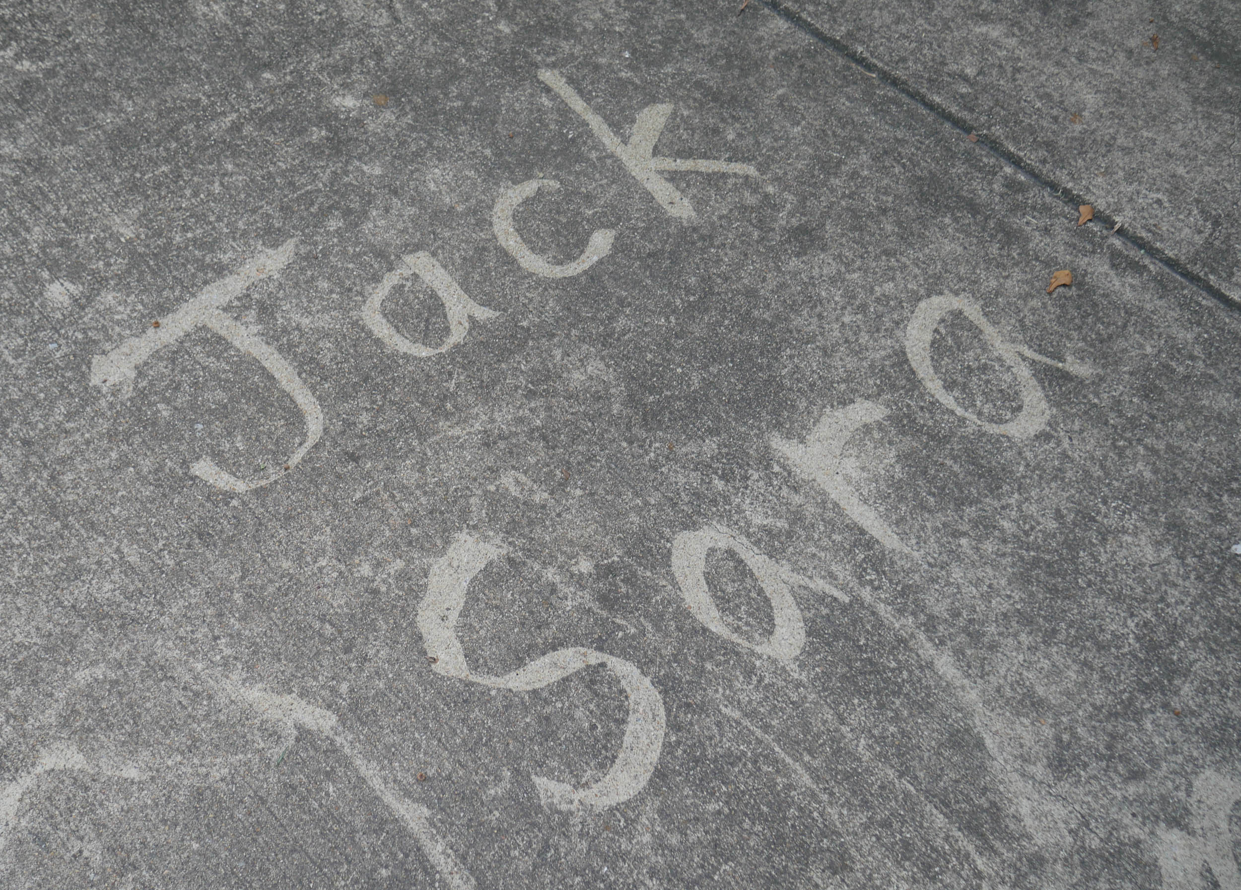 The names “Jack” and “Sara” written on a concrete driveway with a pressure washer.