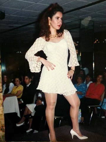 Fuchis’ mother, a model, poses on stage in a mid-thigh-length, white lace dress and high heels.